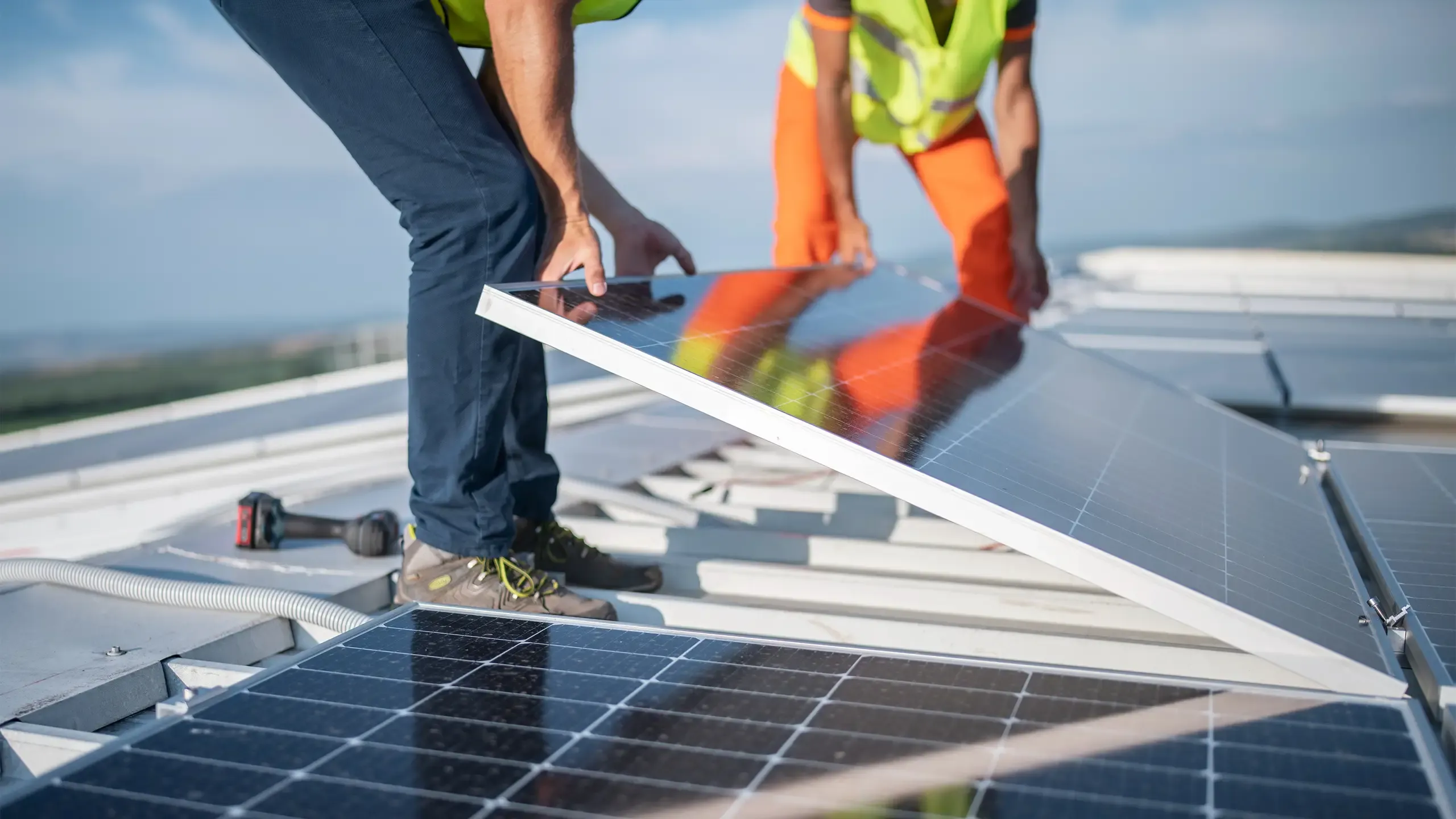 Team of two engineers installing solar panels on roof