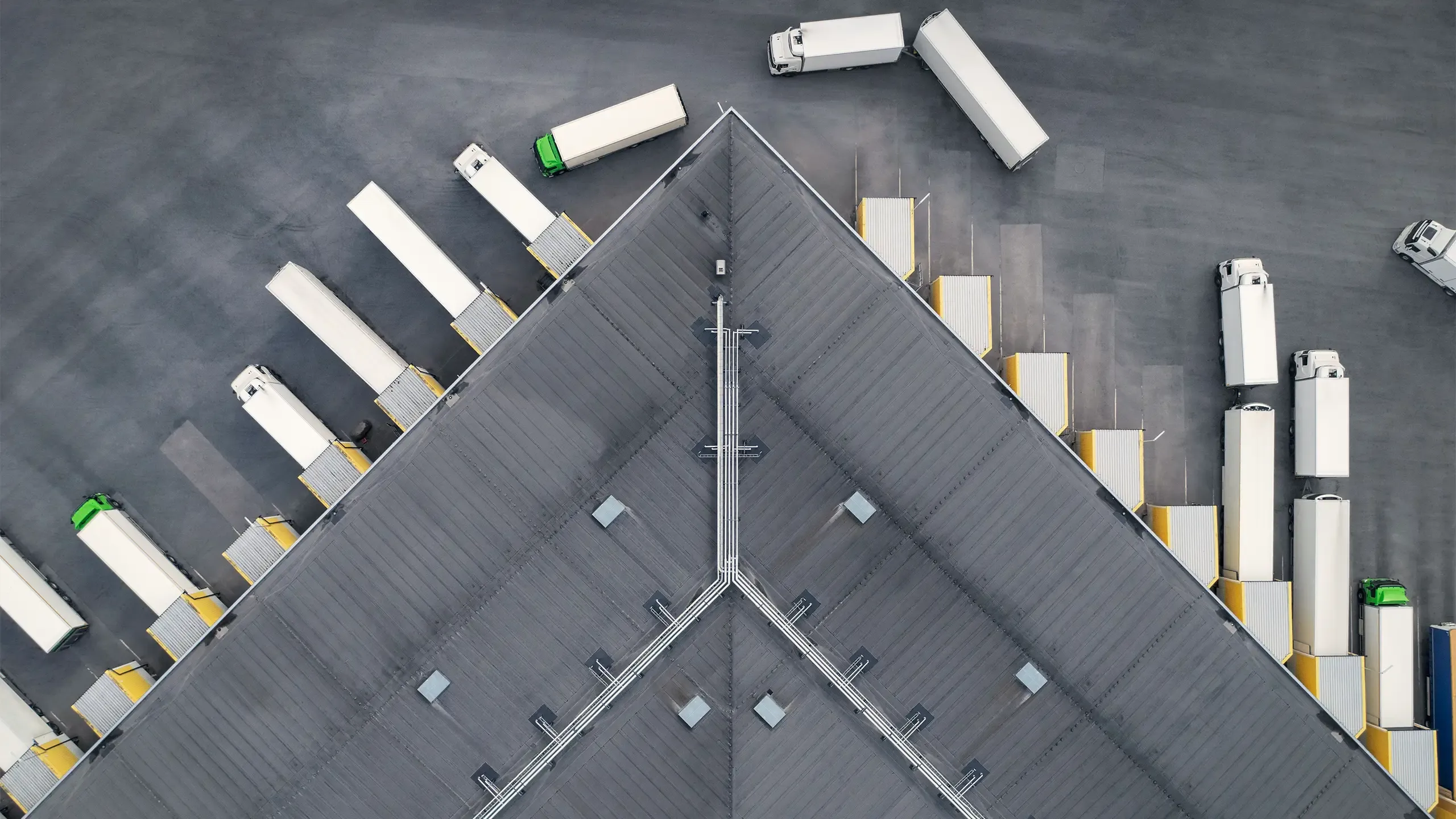Aerial view of a large distribution warehouse with loading docks and many trucks.