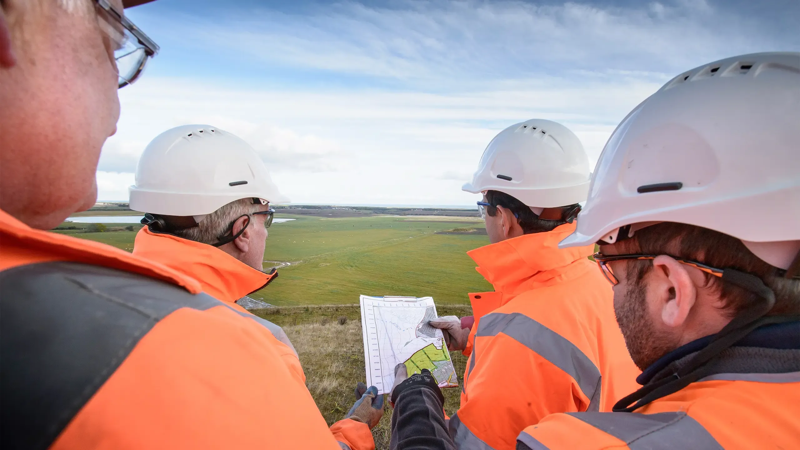 Workers holding plans inspecting land around surface coal mine restoration