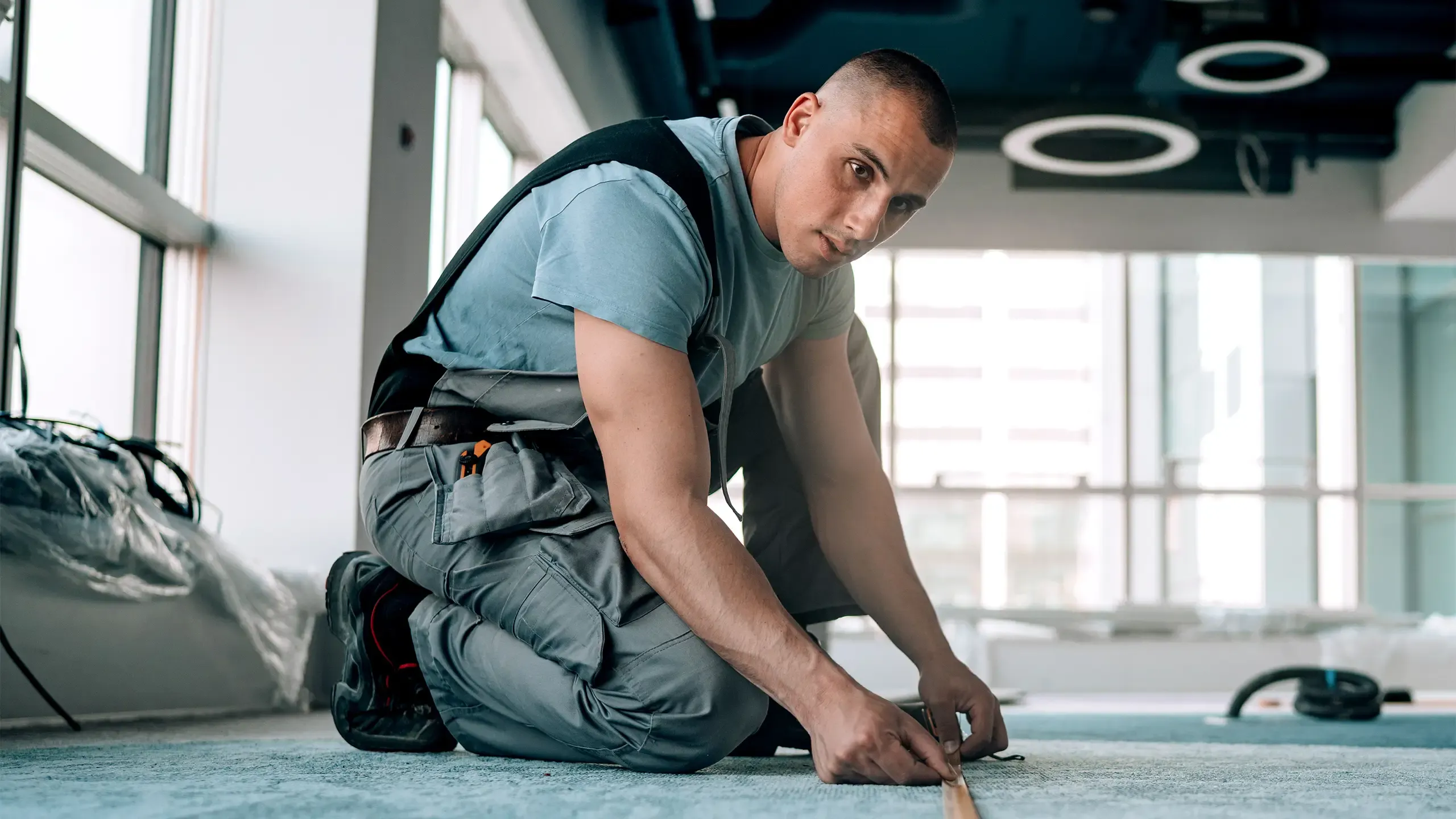 Engaging in calculations, a young man measures the floor to make precise adjustments for a seamless installation