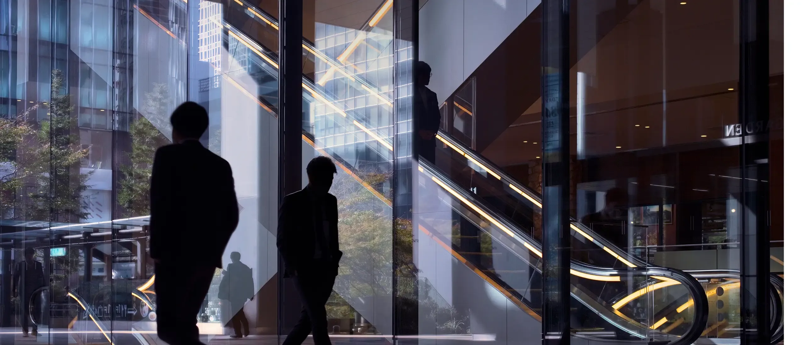 Morning image with office workers passing modern office facade in Tokyo, Japan.