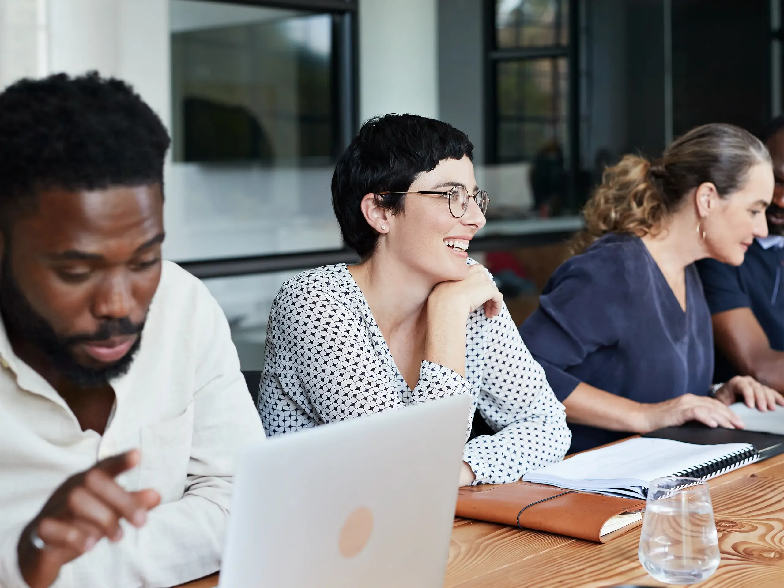Smiling businesswoman sitting with male and female colleagues in meeting at new workplace