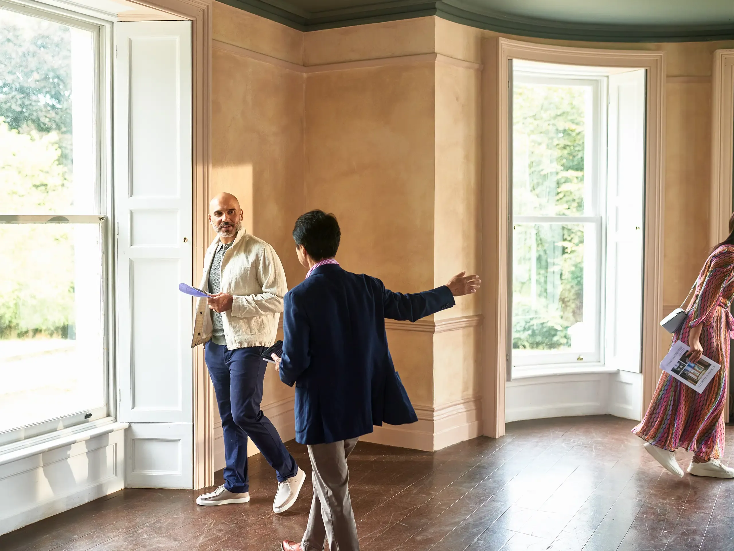 Senior real estate agent showing couple around potential new house pointing out features in spacious empty room, real estate, potential, new life