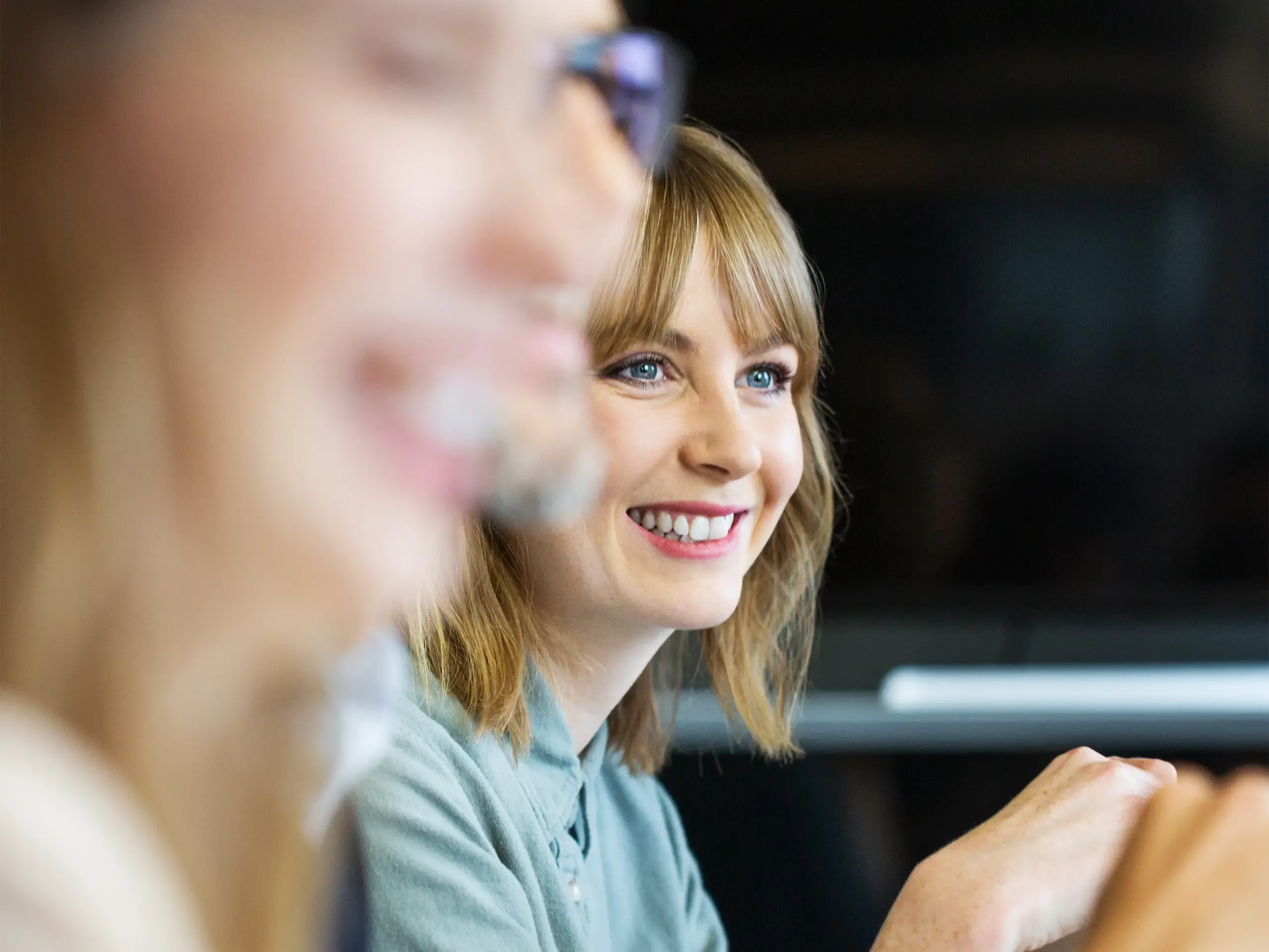 Young businesswoman sitting in meeting and listening to conversation. Female professional listening to colleague in meeting.