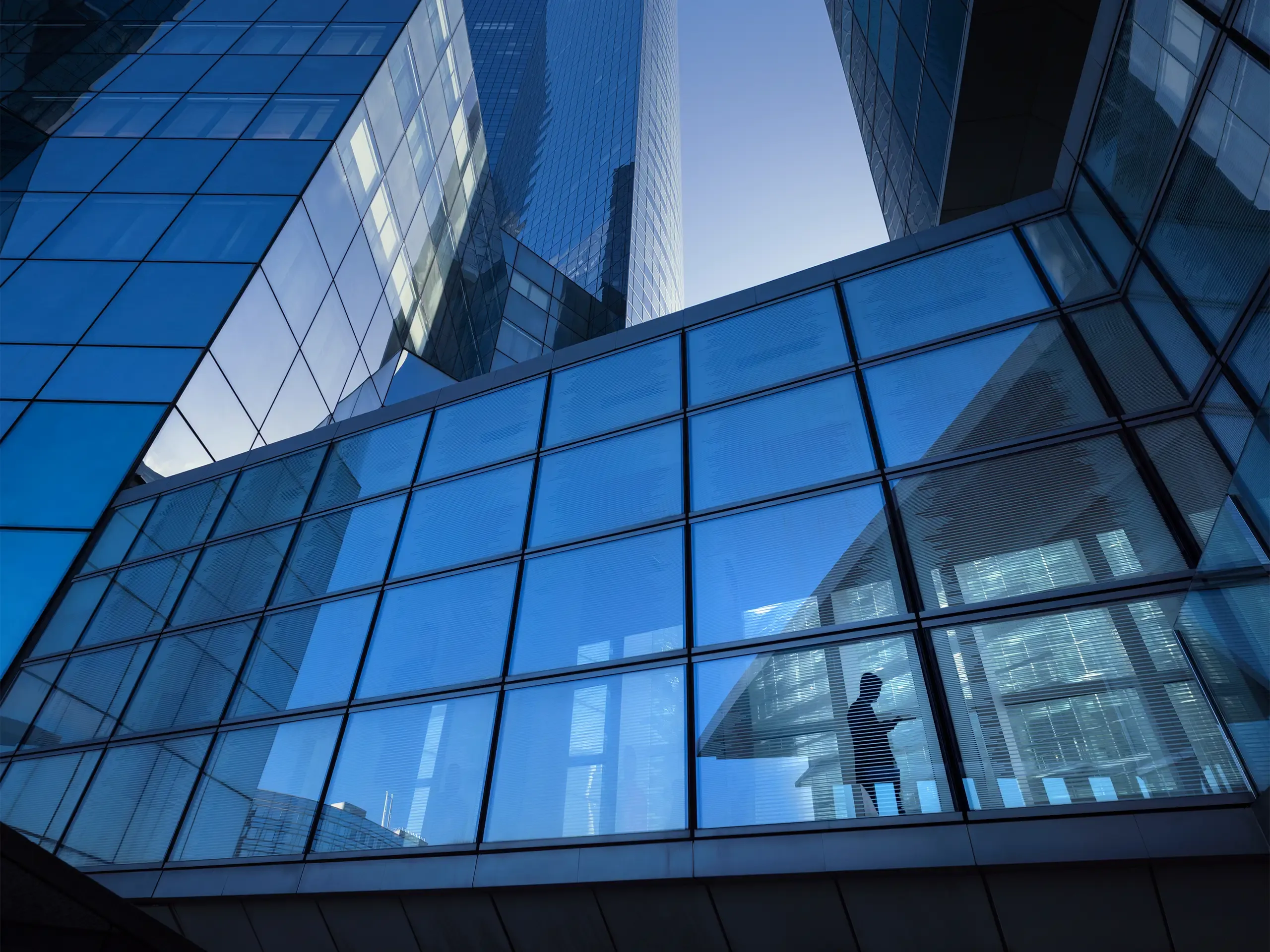 Modern office buildings with silhouette of businessman crossing elevated overpass