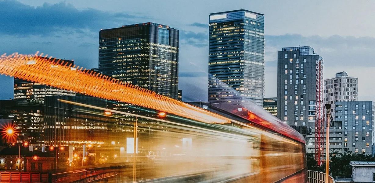 The DLR train passes by in front of a view of the Canary Wharf skyline, London