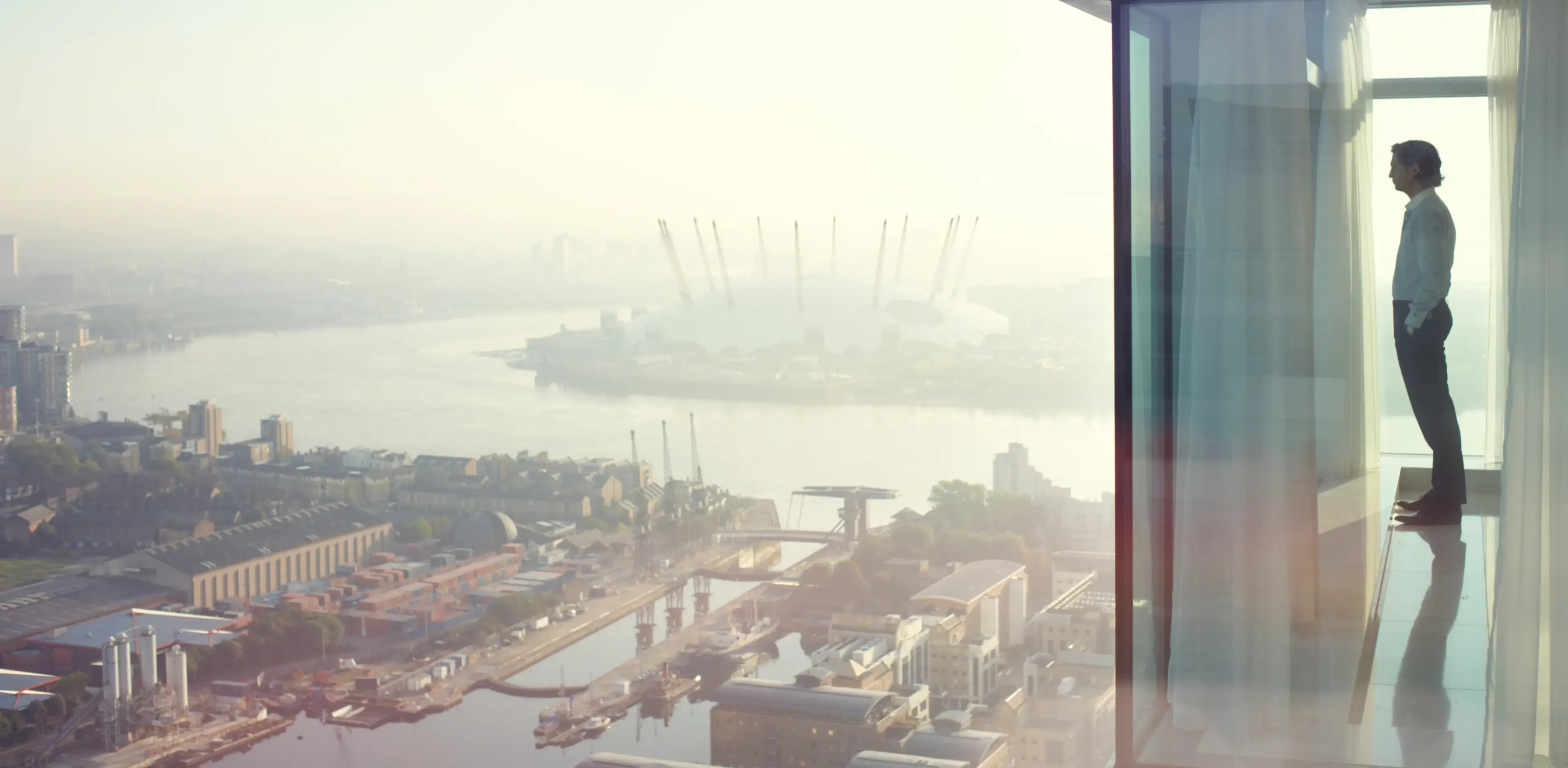 Business executive looking at view from city apartment window early morning