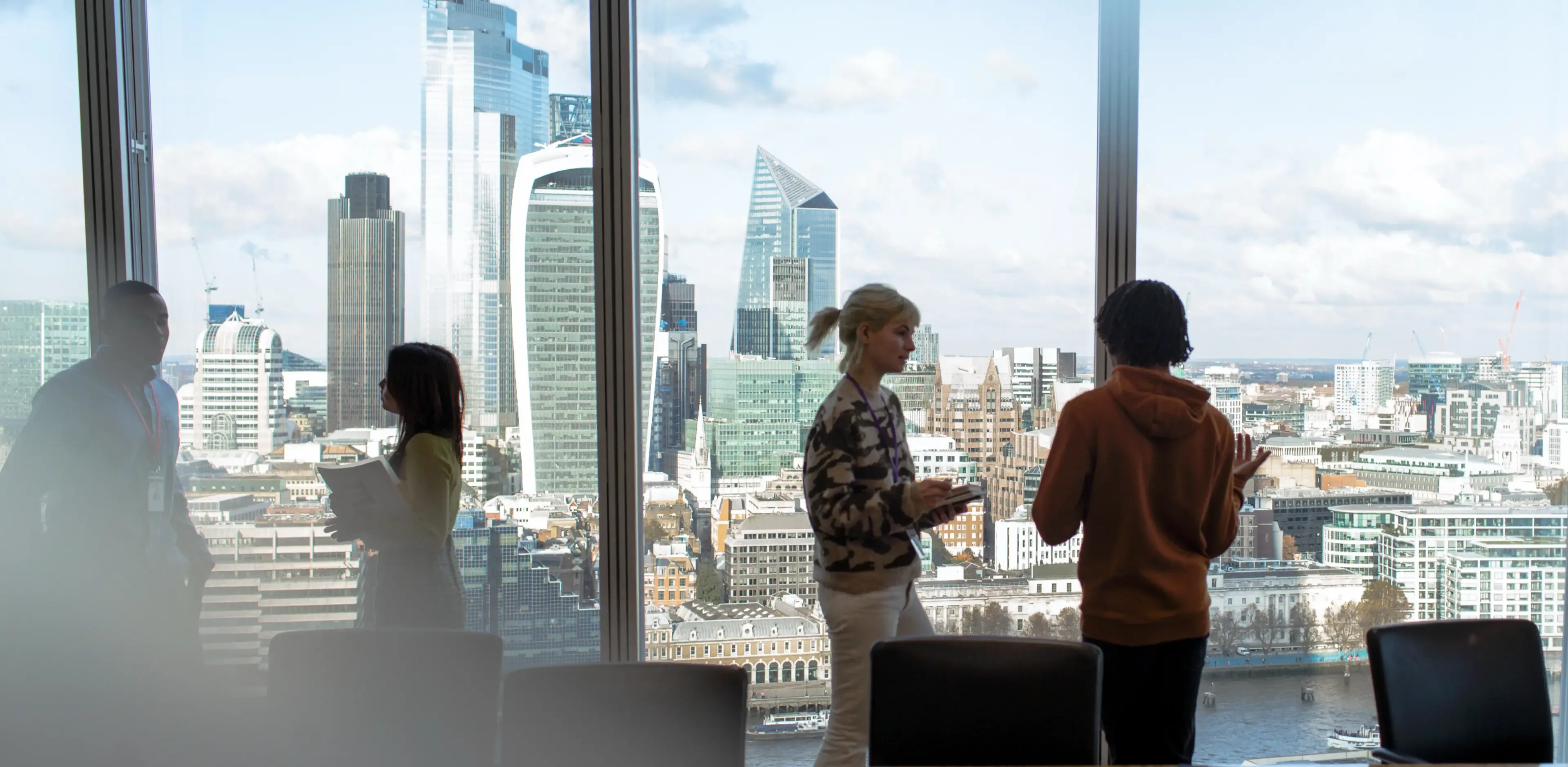 Corporate business people talking at highrise office window with city view, London, UK