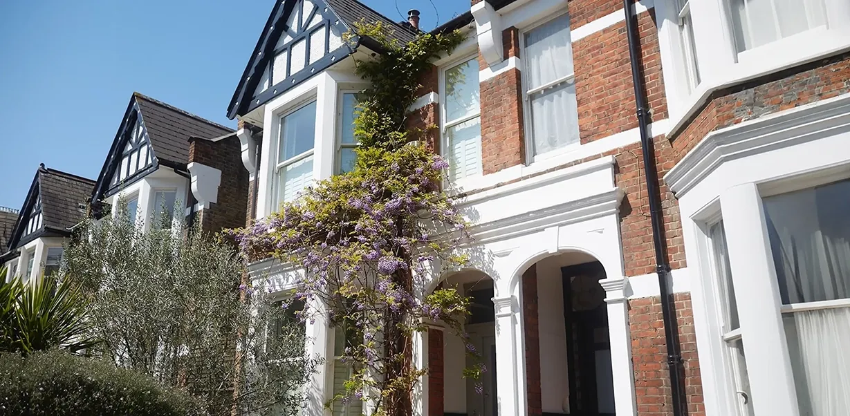 A row of residential houses adjacent to a tree, highlighting the integration of greenery in a neighborhood setting.