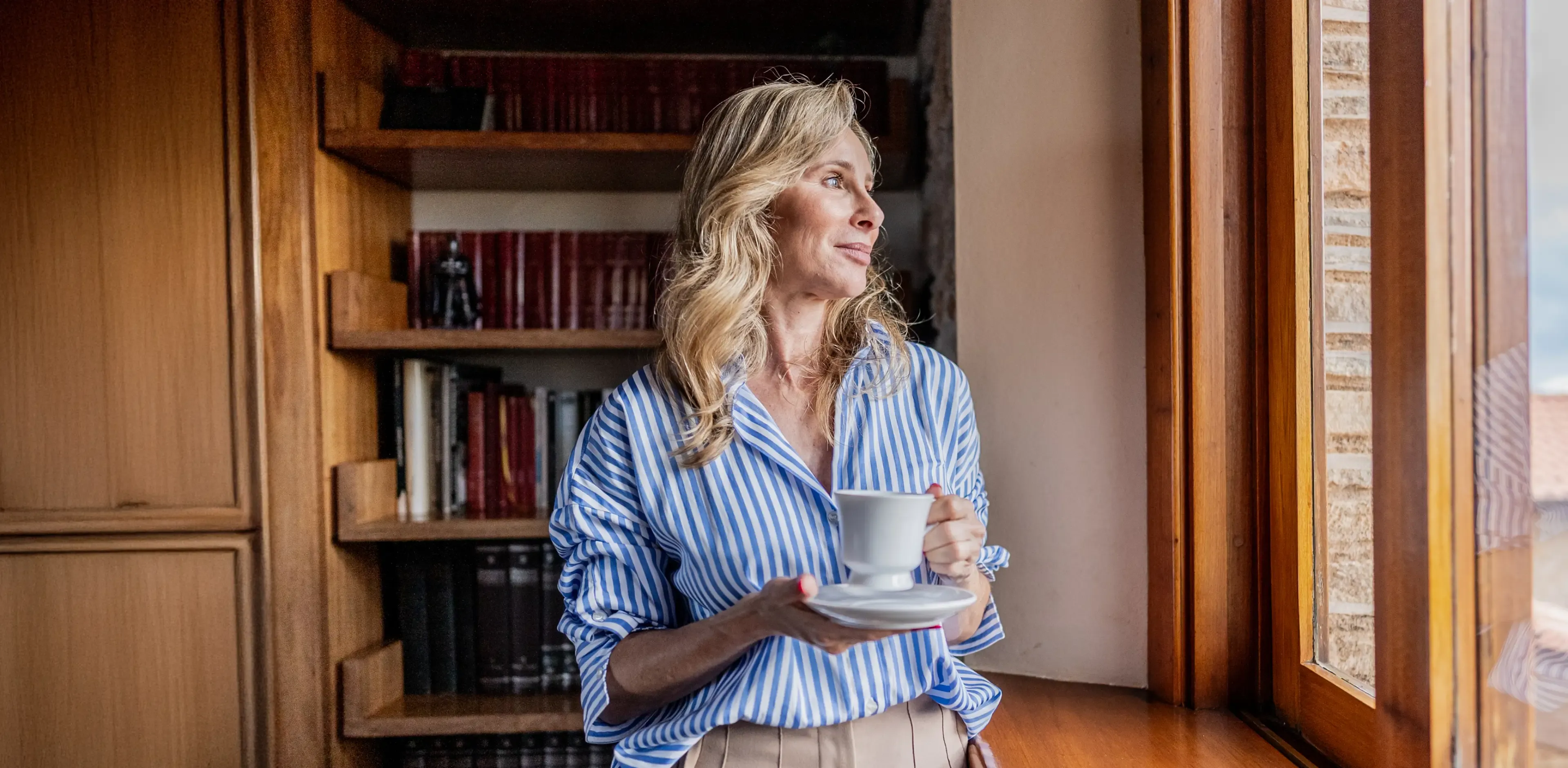 Mature woman contemplating while looking through the window at home