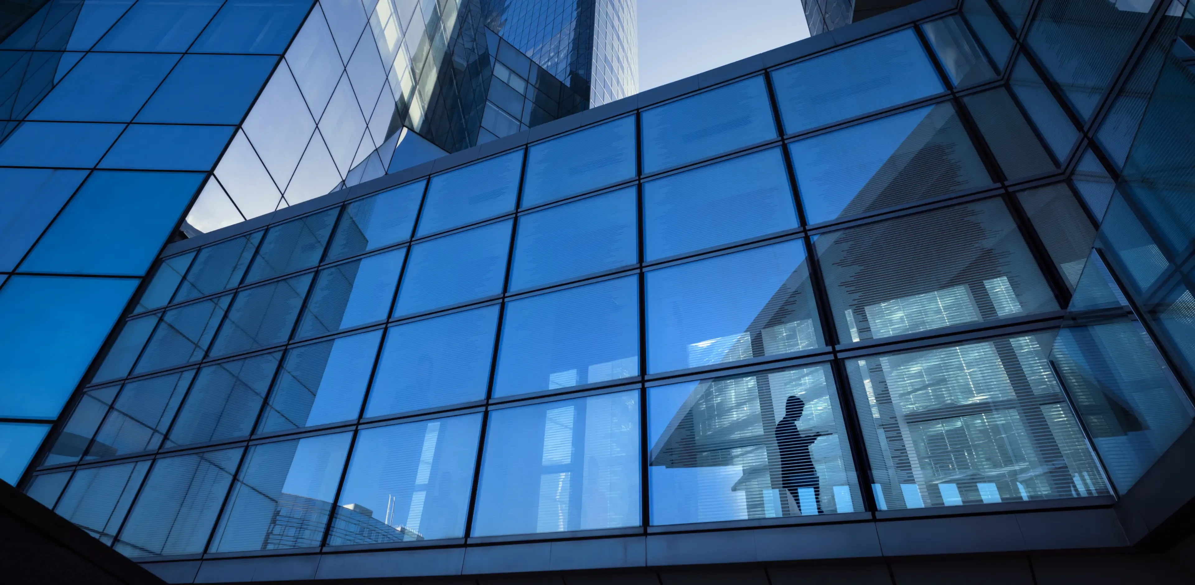 Modern office buildings with silhouette of businessman crossing elevated overpass