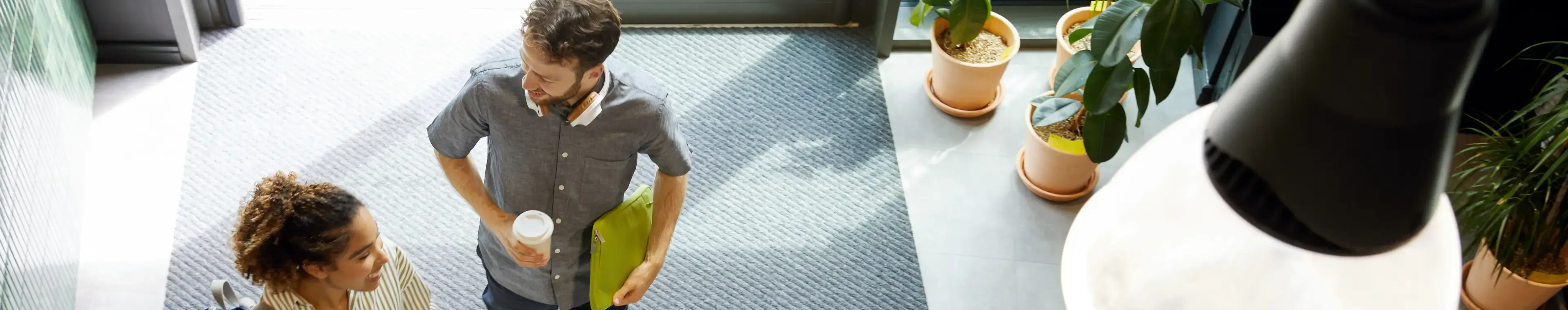 Male and female colleague talking in a modern, sunny office lobby