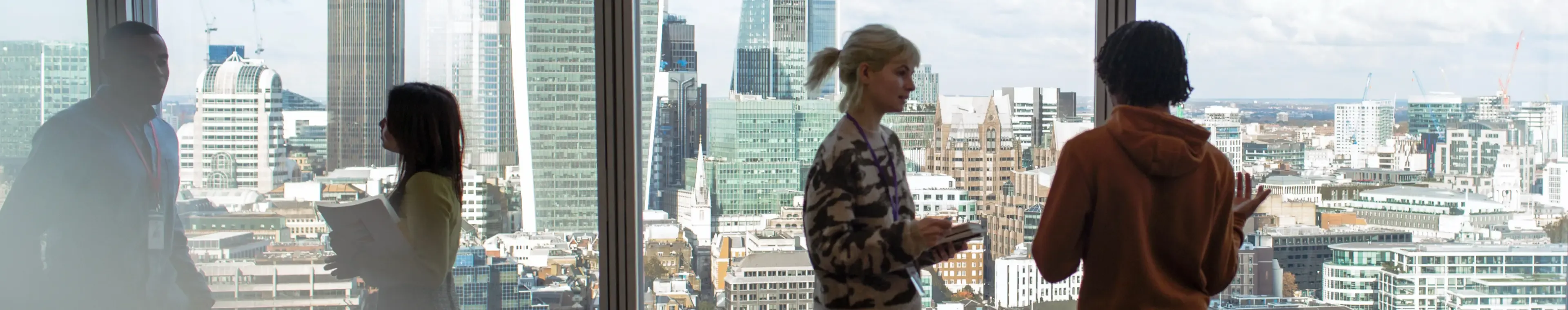 Corporate business people talking at highrise office window with city view, London, UK
