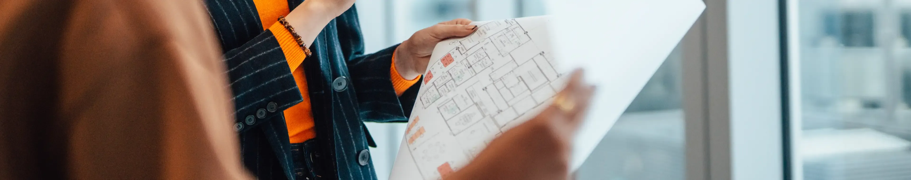 Businesswoman having a discussion with her colleague over the floor plan of an empty office space