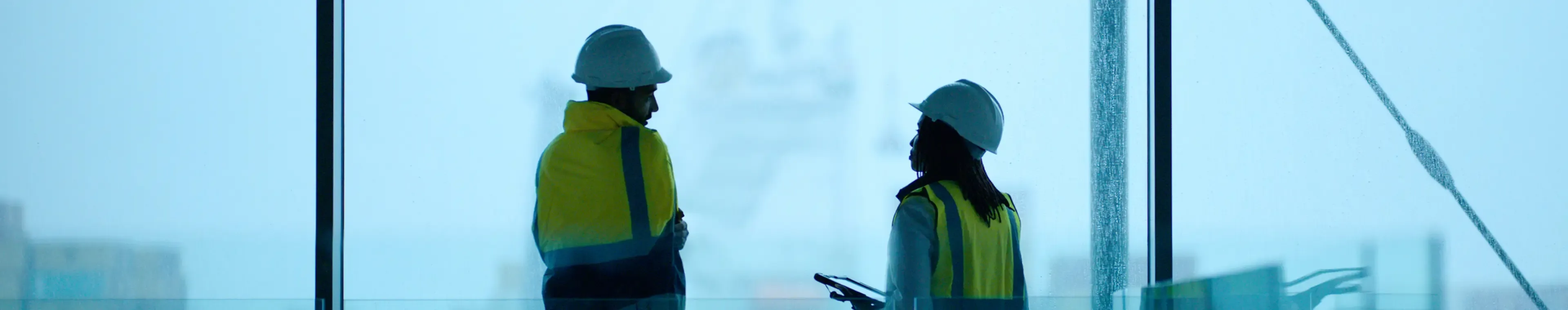Two colleagues in high-visibility vests having a conversation on a construction site