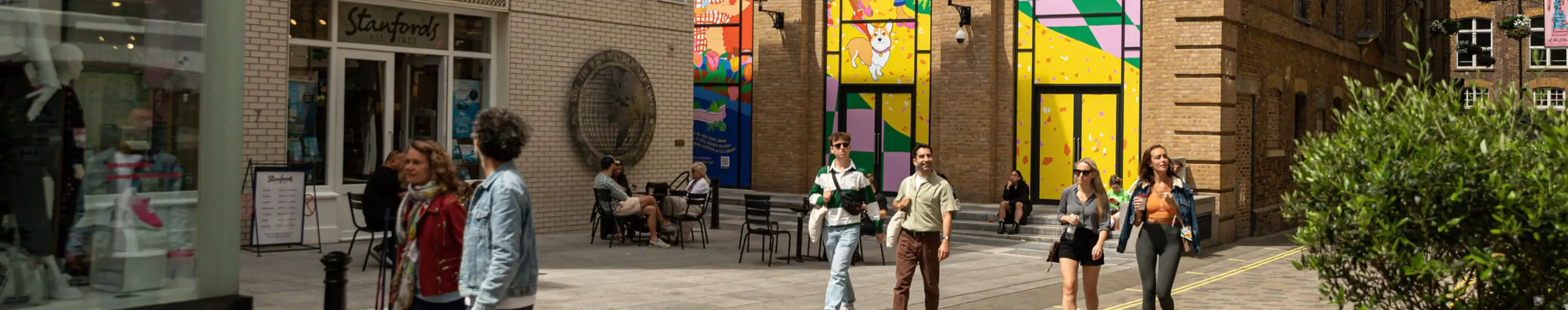 People walking through sunny, colourful street in Covent Garden