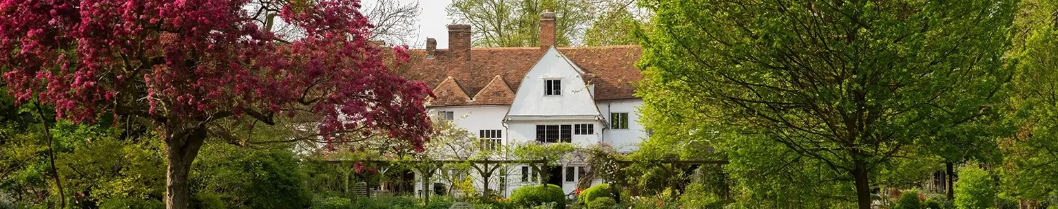 A spacious house set on a lush lawn with a croquet set, with trees providing a natural, peaceful backdrop.