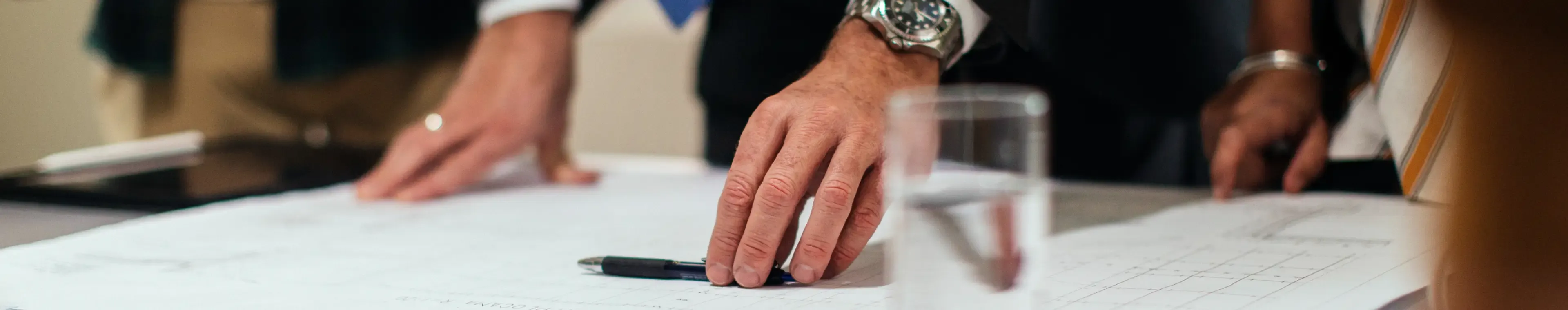 Unrecognisable investors and construction workers discussing architectural plans in the office together