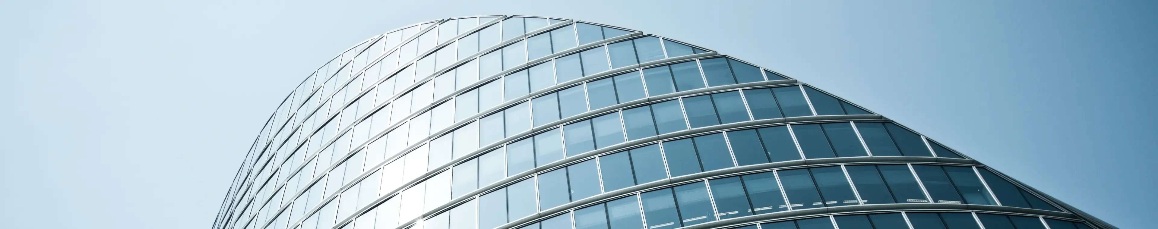 A curved, modern office building against a blue sunny sky