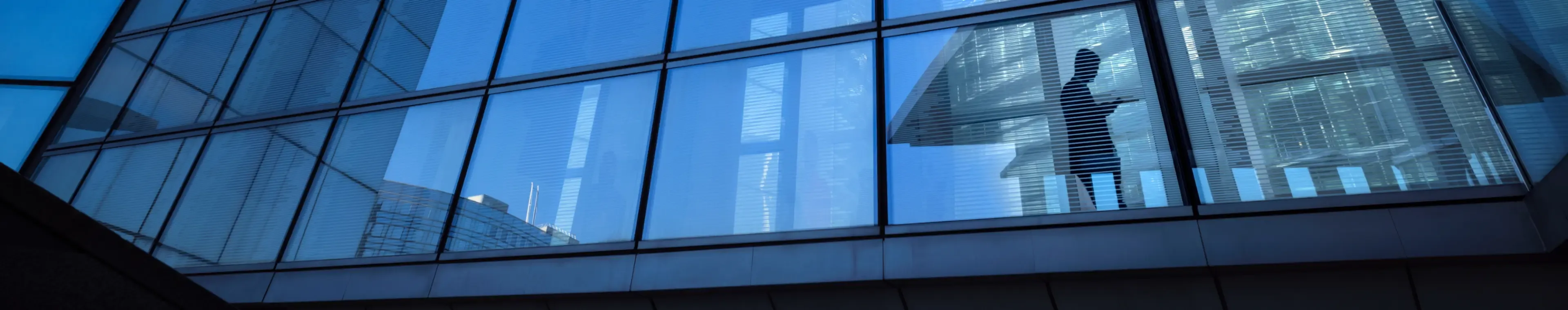 Modern office buildings with silhouette of businessman crossing elevated overpass