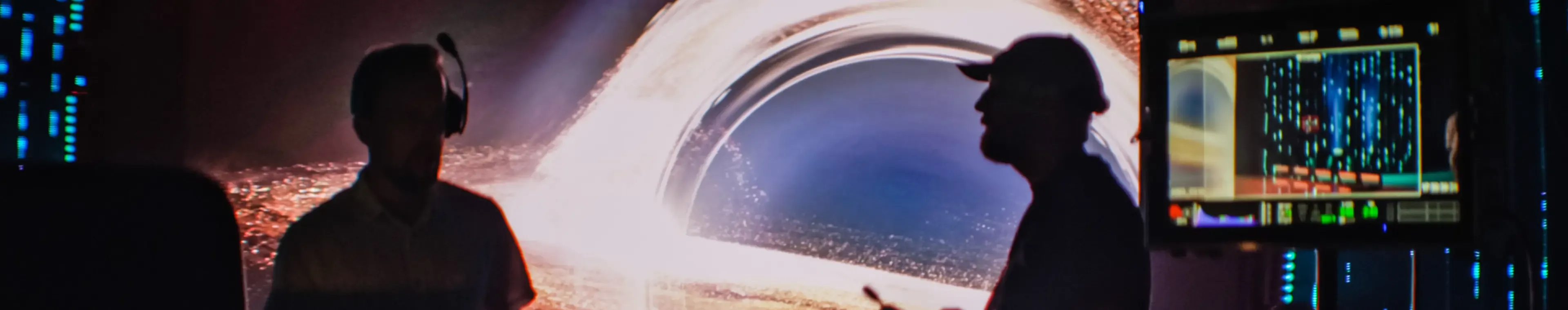 Unrecognisable people working on movie set in foreground. Cameraman, director and assistants silhouettes. Black hole projection