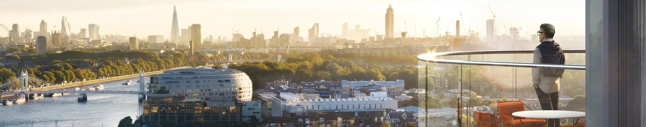 Man looking from his high balcony over the London skyline and Thames River