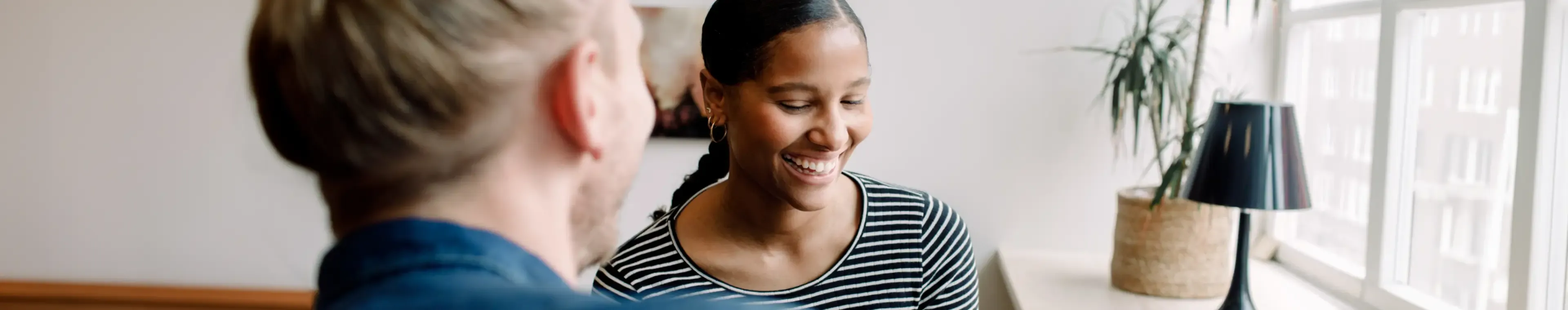 Smiling businesswoman looking at camera while sitting with colleague by desk in office