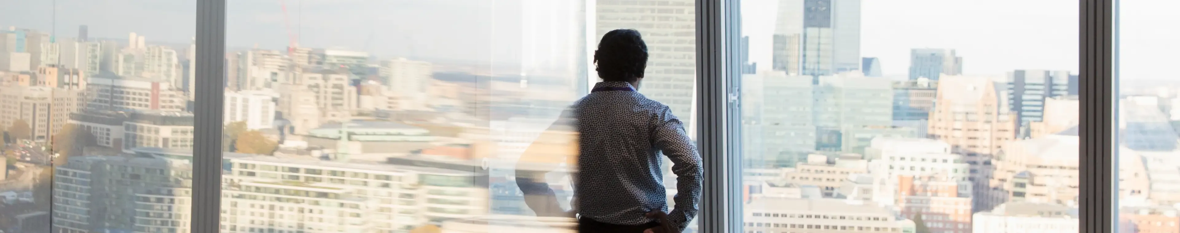 Thoughtful corporate businessman looking out highrise office window at city view, London, UK, multiple exposure