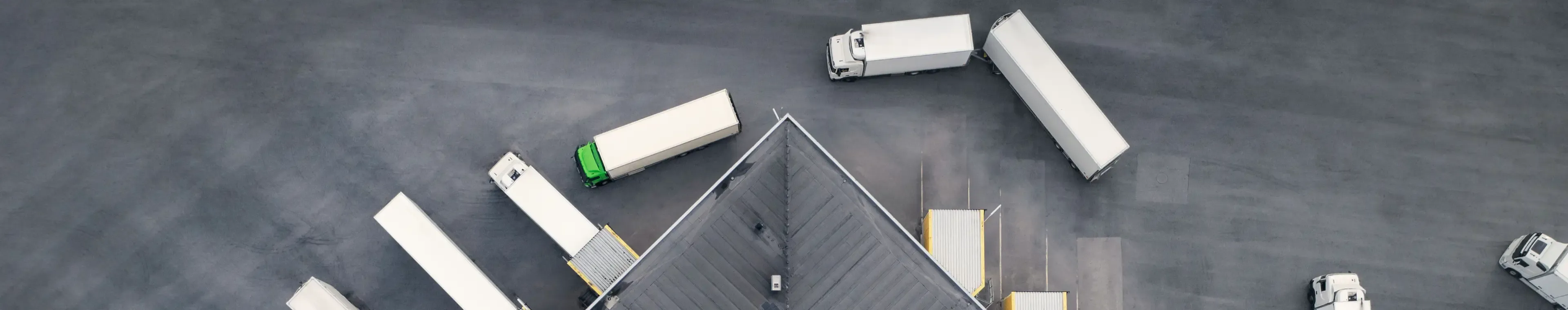 Aerial view of a large distribution warehouse with loading docks and many trucks.