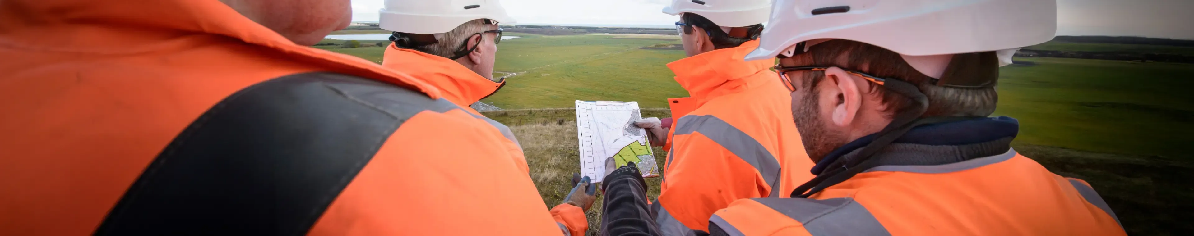 Workers holding plans inspecting land around surface coal mine restoration