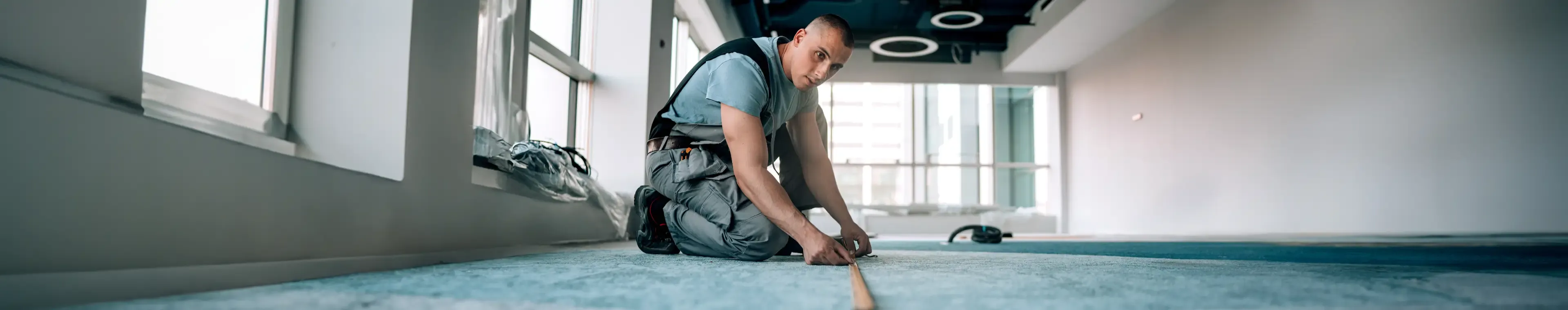 Engaging in calculations, a young man measures the floor to make precise adjustments for a seamless installation