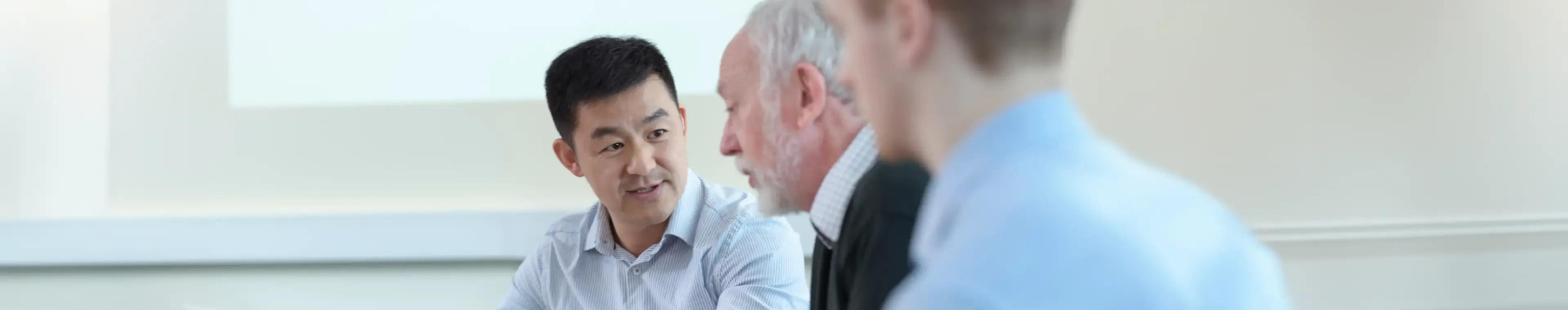 Younger and older scientists discussing pharmaceutical science project in meeting room
