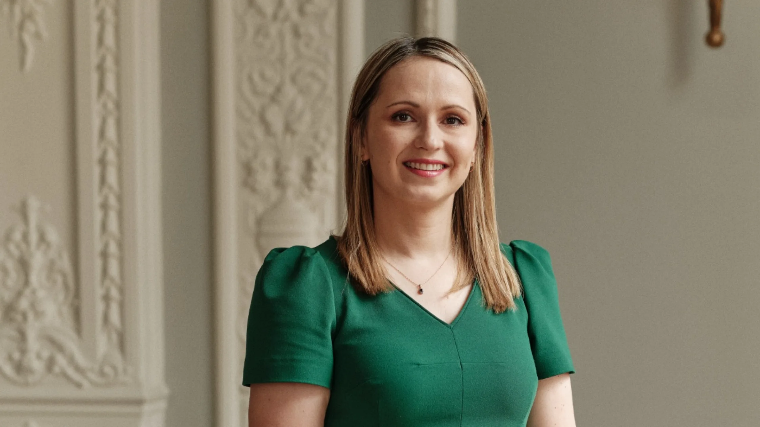 A woman with blonde hair in a green dress looking at the camera